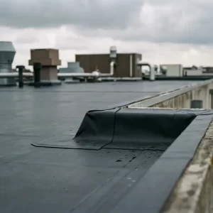 Donker antraciet EPDM rubber dakbedekking op plat commercieel dak met strak gevouwen randen langs de dakrand, bewolkte Nederlandse lucht op de achtergrond.