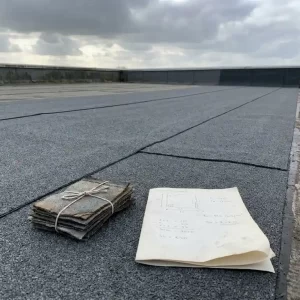 Plat commercieel dak met verse bitumenmembraan naden, materiaalstalen en gevouwen offerte op het dakoppervlak, bewolkte Nederlandse lucht.