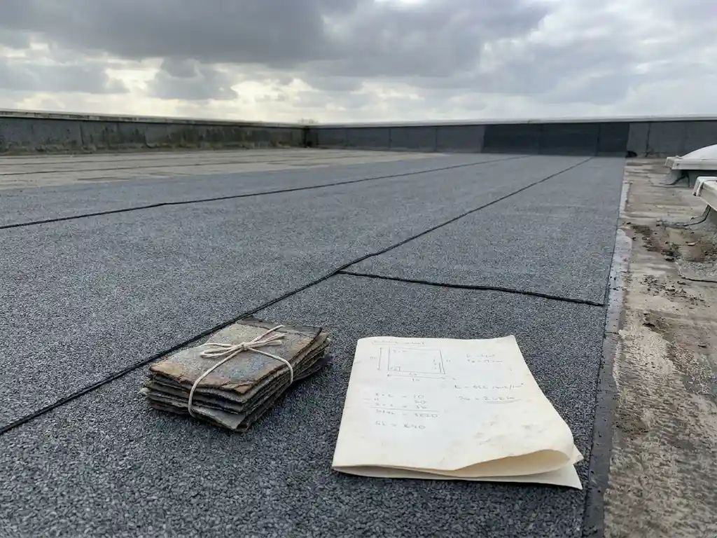 Plat commercieel dak met verse bitumenmembraan naden, materiaalstalen en gevouwen offerte op het dakoppervlak, bewolkte Nederlandse lucht.
