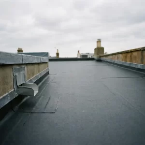Plat dak met vers aangebrachte zwarte EPDM-membraan, strakke afwerkingsranden en afvoerpunten onder bewolkte Nederlandse lucht.