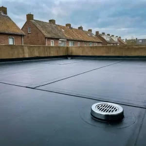 Nieuw aangelegd EPDM dakmembraan met afgewerkte naden en chromen afvoerput op een plat dak in Nederlandse buitenwijk.