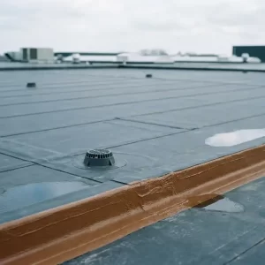Plat EPDM-dak van een commercieel gebouw met zichtbare naden, afvoerpunten en vers afgewerkte dakrand in bewolkt daglicht.