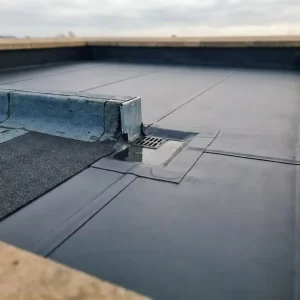 Bovenaanzicht van een plat dak met EPDM-membraan, nette naden, dakafvoer en vers aangebracht dakdichtingsfolie naast verouderd materiaal.