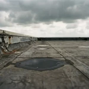 Verweerde EPDM-dakbedekking op commercieel plat dak met naadlijnen, waterplassen en gesleten dakranddetails onder bewolkte Nederlandse lucht.