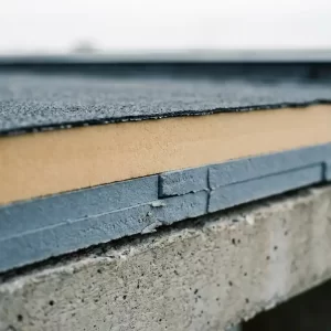 Dwarsdoorsnede van een plat dakrand met bitumineuze dakbedekking, twee lagen isolatieplaten en betonnen ondergrond.