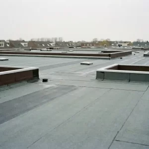 Nieuw aangebrachte dakbedekking op groot Nederlands woongebouw met zichtbare naden, afvoerpunten en randafwerking.