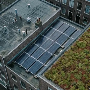 Luchtfoto van drie platte daken op aangrenzende Nederlandse bedrijfspanden met bitumen dakbedekking, sedum begroeide daklaag en zonnepanelen.